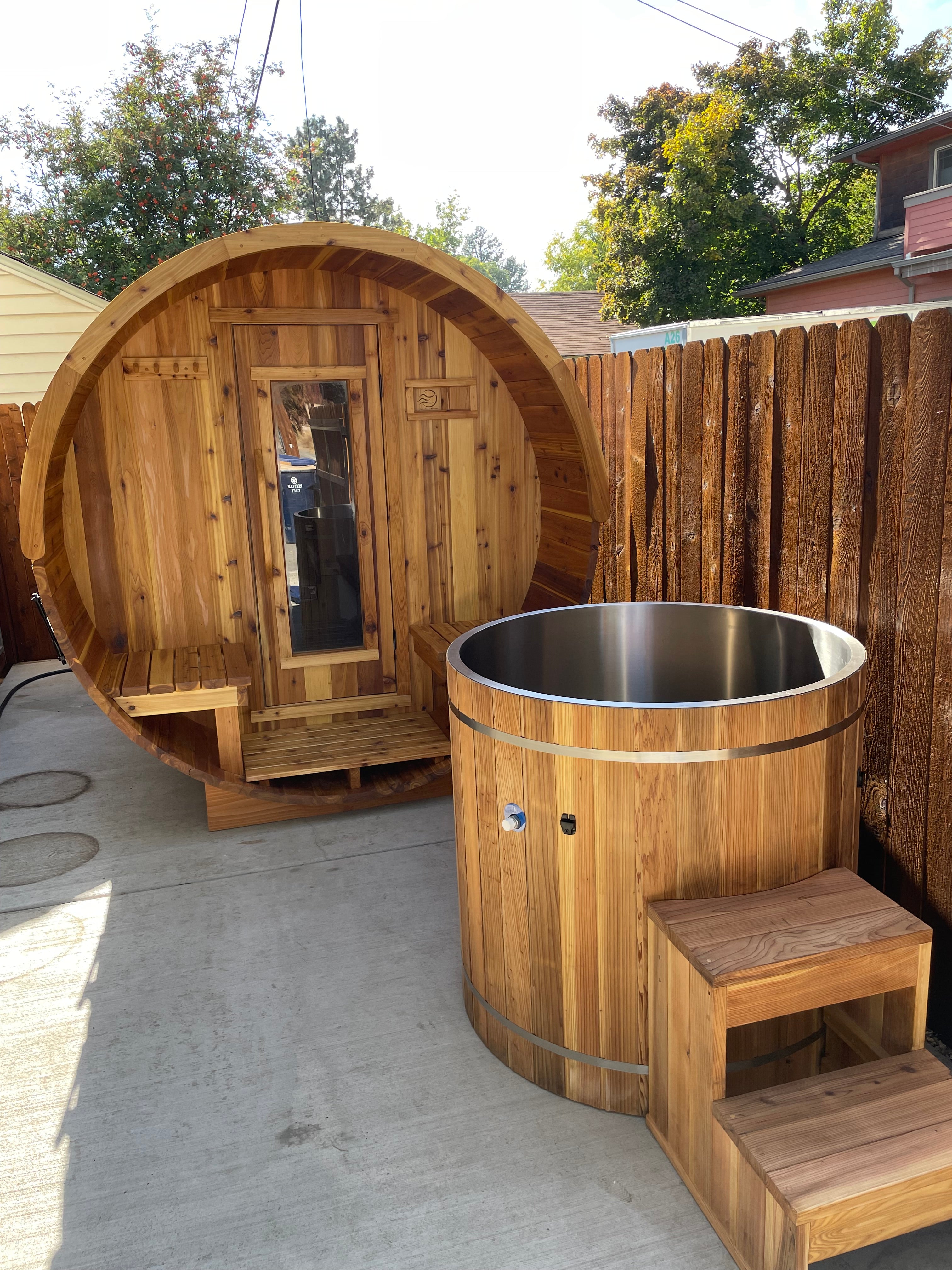 stainless steel cold plunge and wood barrel sauna in backyard