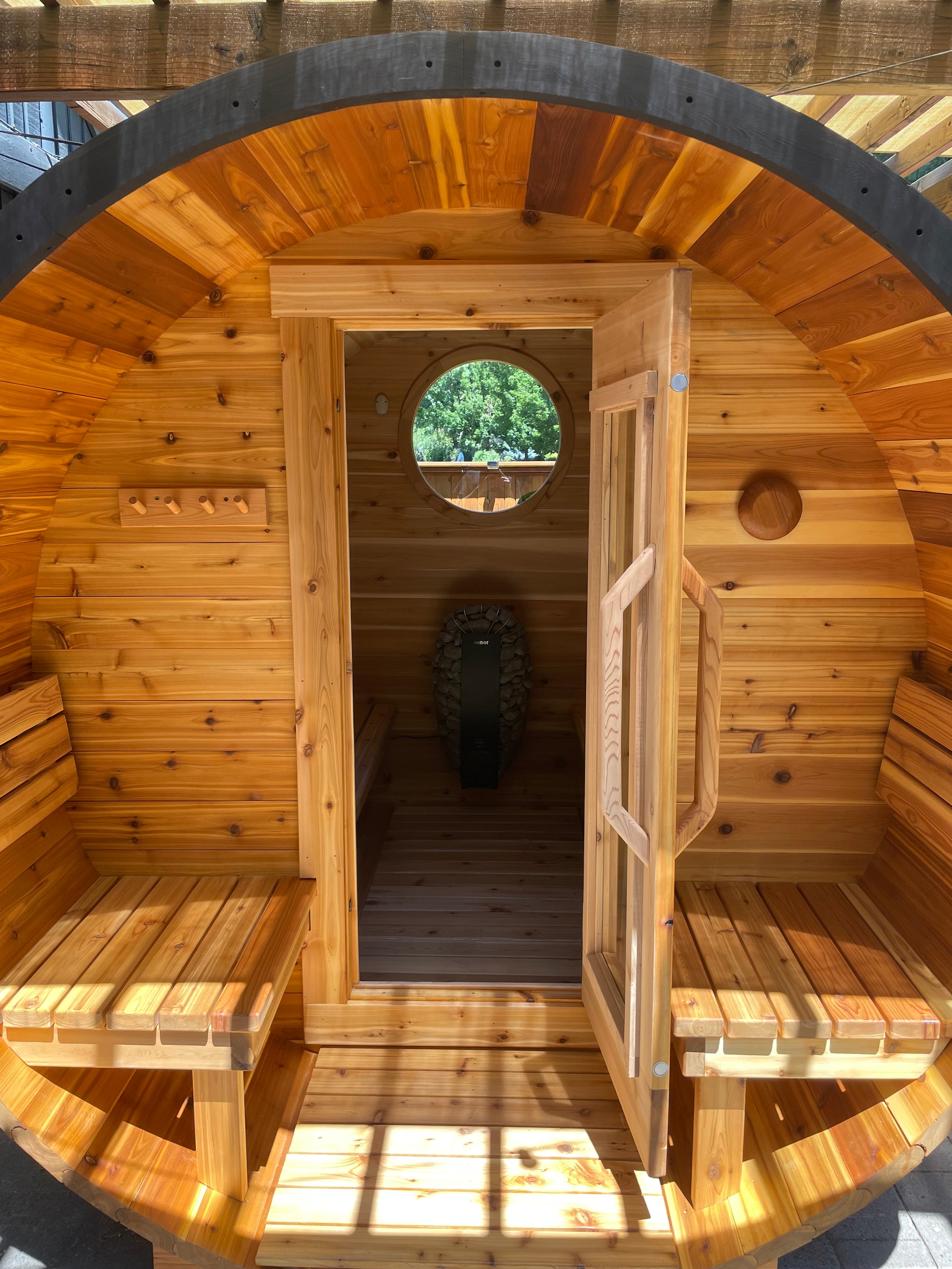 Wooden barrel sauna with a circular window and benches inside