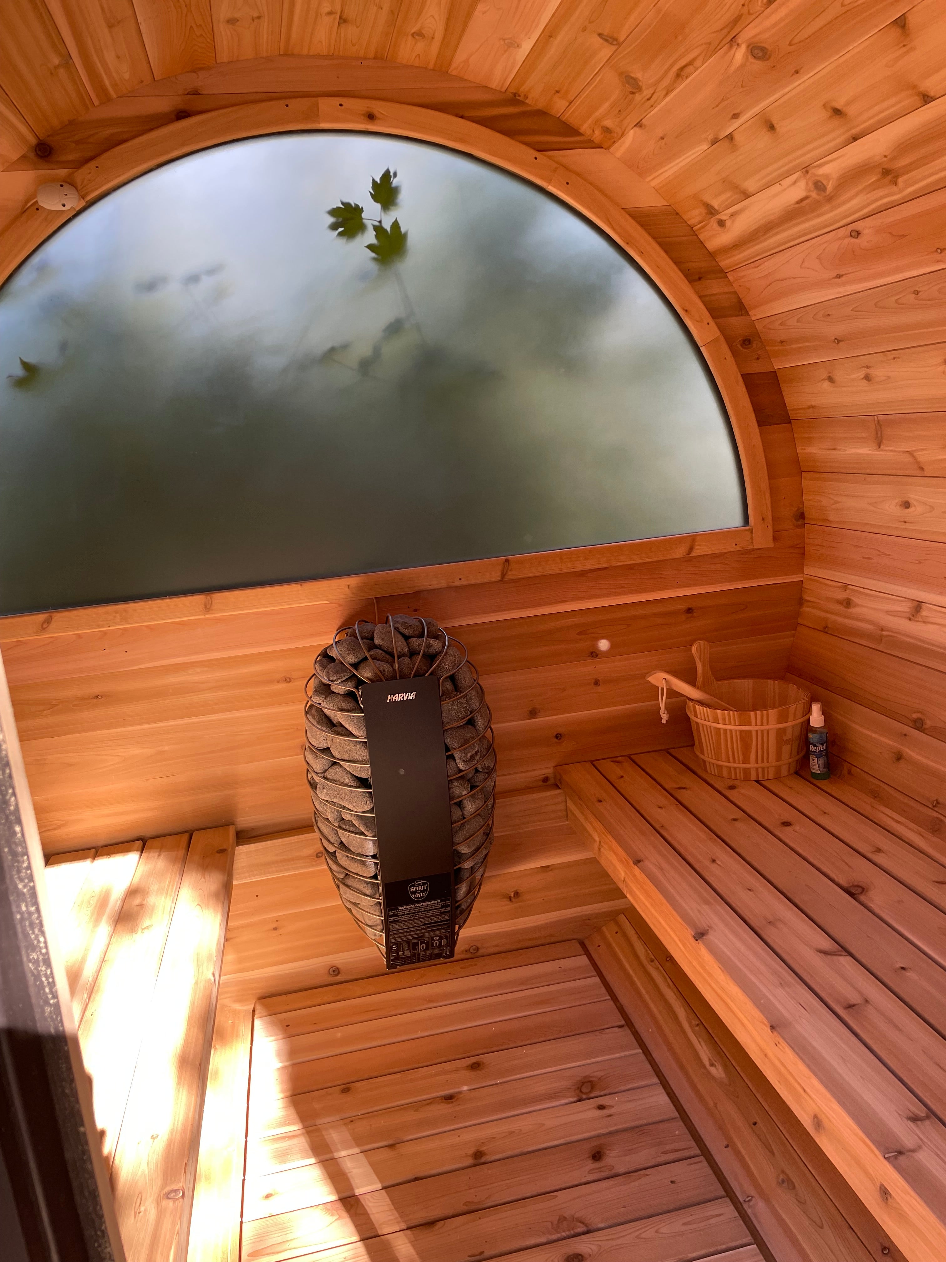 Backyard sauna with half moon round window and stone electric heater